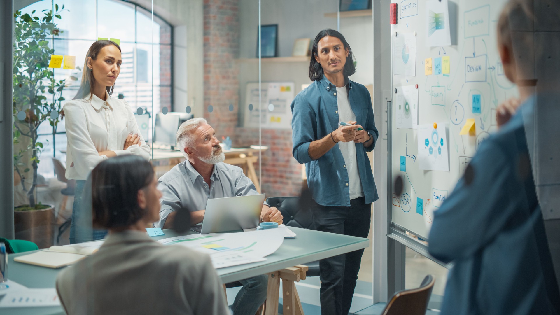 Multiethnic Business Team Discussing Strategy in a Meeting Room at the Office. Latin Male Designer Brainstorming with Heads of Departments and Deciding on a Marketing campaign for New Product Launch